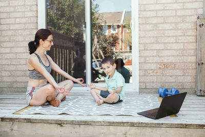 Family sport activity. middle age caucasian mother with toddler son doing distant remote online yoga 