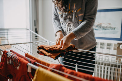 Midsection of woman holding clothes on clothesline at home