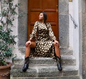 Full length of woman sitting against door