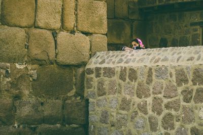 Rear view of man climbing on retaining wall