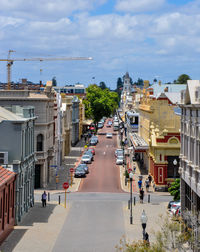 Vehicles on street amidst buildings in city against sky