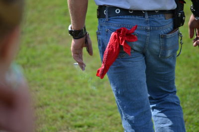 Midsection of couple holding hands on field