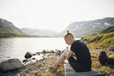 Woman sitting at lake in mountains