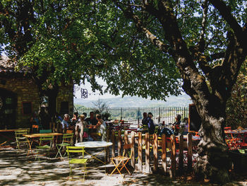 Group of people sitting on table against trees