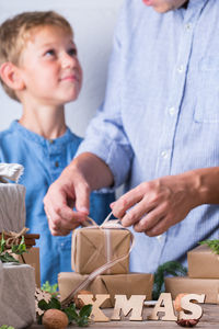 Midsection of father tying ribbon on gift with son