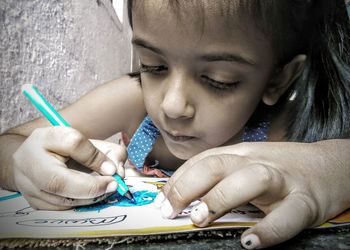 Close-up of girl drawing while sitting at home