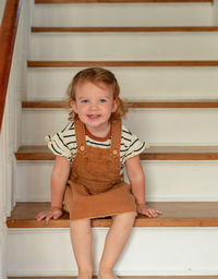 Portrait of cute girl sitting on staircase at home