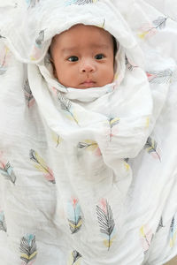 A cute 3 month asian baby smiling and happy with swaddled.