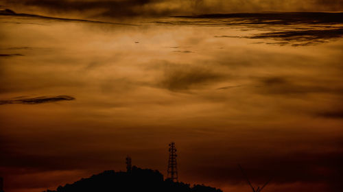 Silhouette cranes against sky during sunset