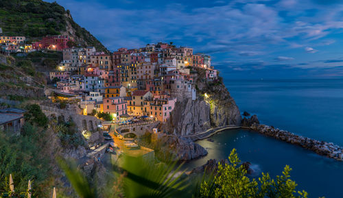 High angle view of illuminated buildings by sea against sky