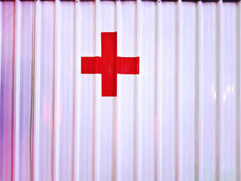Red cross sign on white corrugated cargo container wall