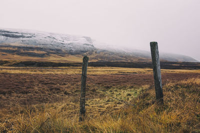 Wooden fence on field against sky