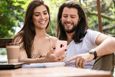 Smiling couple using mobile phone outdoors