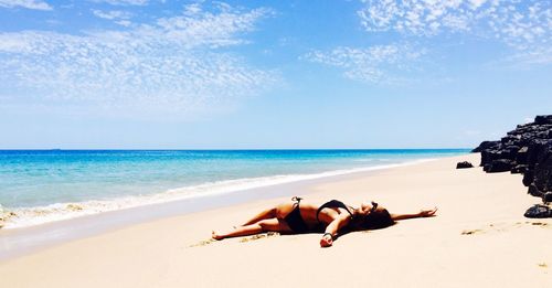 Full length of young woman on beach against sky