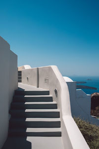 Buildings by sea against clear blue sky