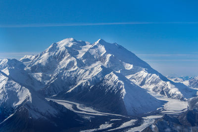 Scenic view of snowcapped mountains against blue sky