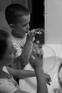 High angle view of siblings blowing bubbles in bathroom
