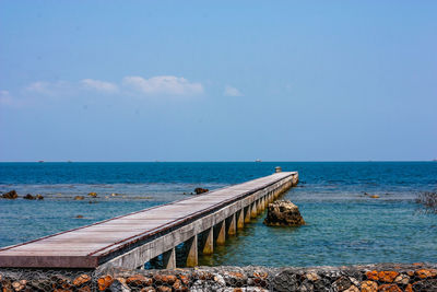 Scenic view of sea and wooden deck platform against sky