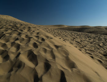 Sand dunes in desert against clear sky