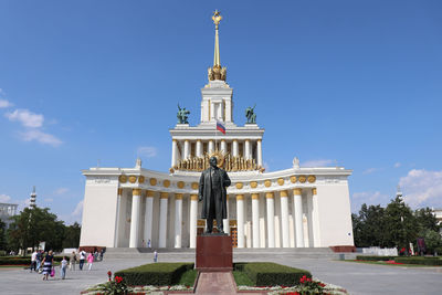 Statue in city against sky