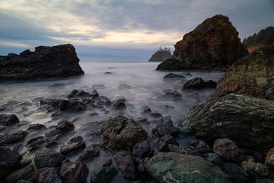 Rocks on beach against sky during sunset