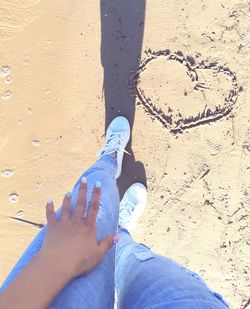 Low section of man standing on sand