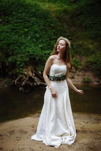 Beautiful woman in white dress standing at lakeshore