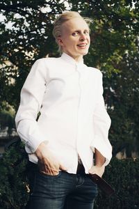 Portrait of woman standing on grass against trees