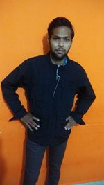 Portrait of young man standing against wall