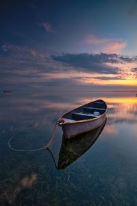 Boat moored on beach against sky during sunset