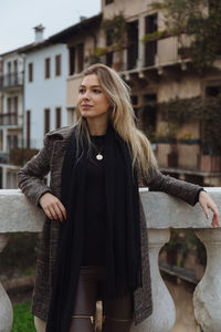 Woman standing at retaining wall against buildings