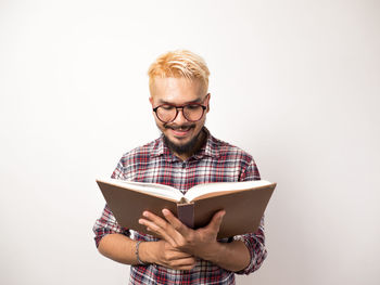 Young man holding book against white background