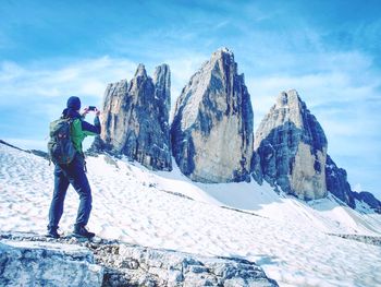 Hiker with backpack takes photos of tre cime with smart phone. summits of dolomites alps mountains