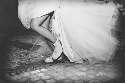 Low section of bride wearing shoes standing on cobbled street