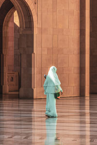 Full length rear view of woman walking on wooden floor