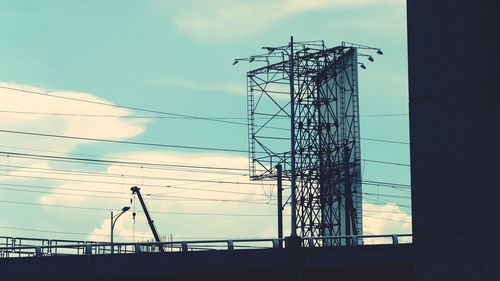 Low angle view of silhouette electricity pylon against sky