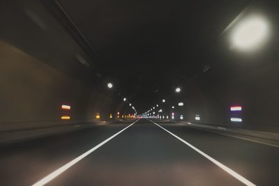 Road in illuminated tunnel at night