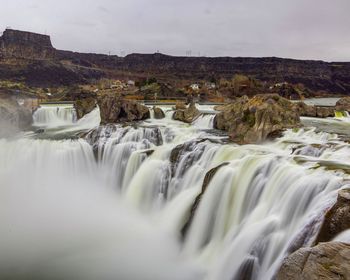 Scenic view of waterfall against sky