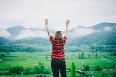 Rear view of man standing on mountain against sky