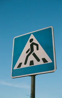 Low angle view of road sign against blue sky