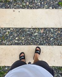 Low section of woman standing on pebbles