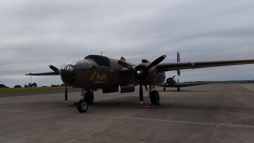 Airplane on airport runway against cloudy sky