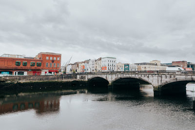 Bridge over river against cloudy sky