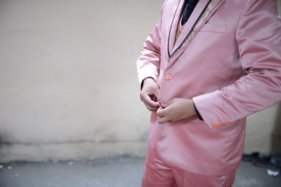 Midsection of man holding pink while standing against city in background