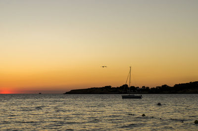 Silhouette sailboat in sea against sky during sunset