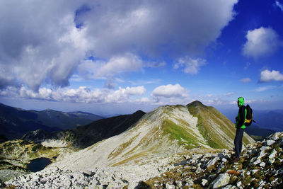 Rear view of man standing by mountains against sky