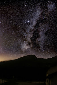 Silhouette mountain against star field sky at night