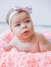 Portrait of cute baby girl lying on bed