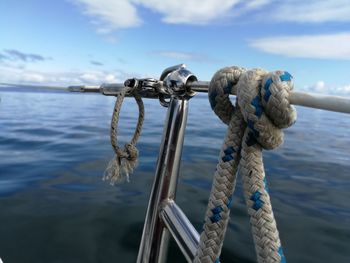 Close-up of ropes tied on metallic bollard against sea