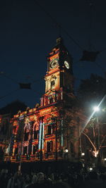 Low angle view of illuminated clock tower at night